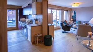 A modern kitchen with wooden cabinets and a dining area with a sofa and a table. - Villars Soleil B 13/14 by Interhome (Villars)
