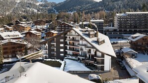 A ski resort with wooden buildings, a central building with balconies, and a mountainous backdrop. - Villars Soleil B 13/14 by Interhome (Villars)