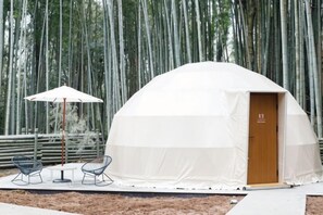 A dome-shaped tent with a door, a table with chairs, and an umbrella. - THE BAMBOO FOREST (Ichihara)