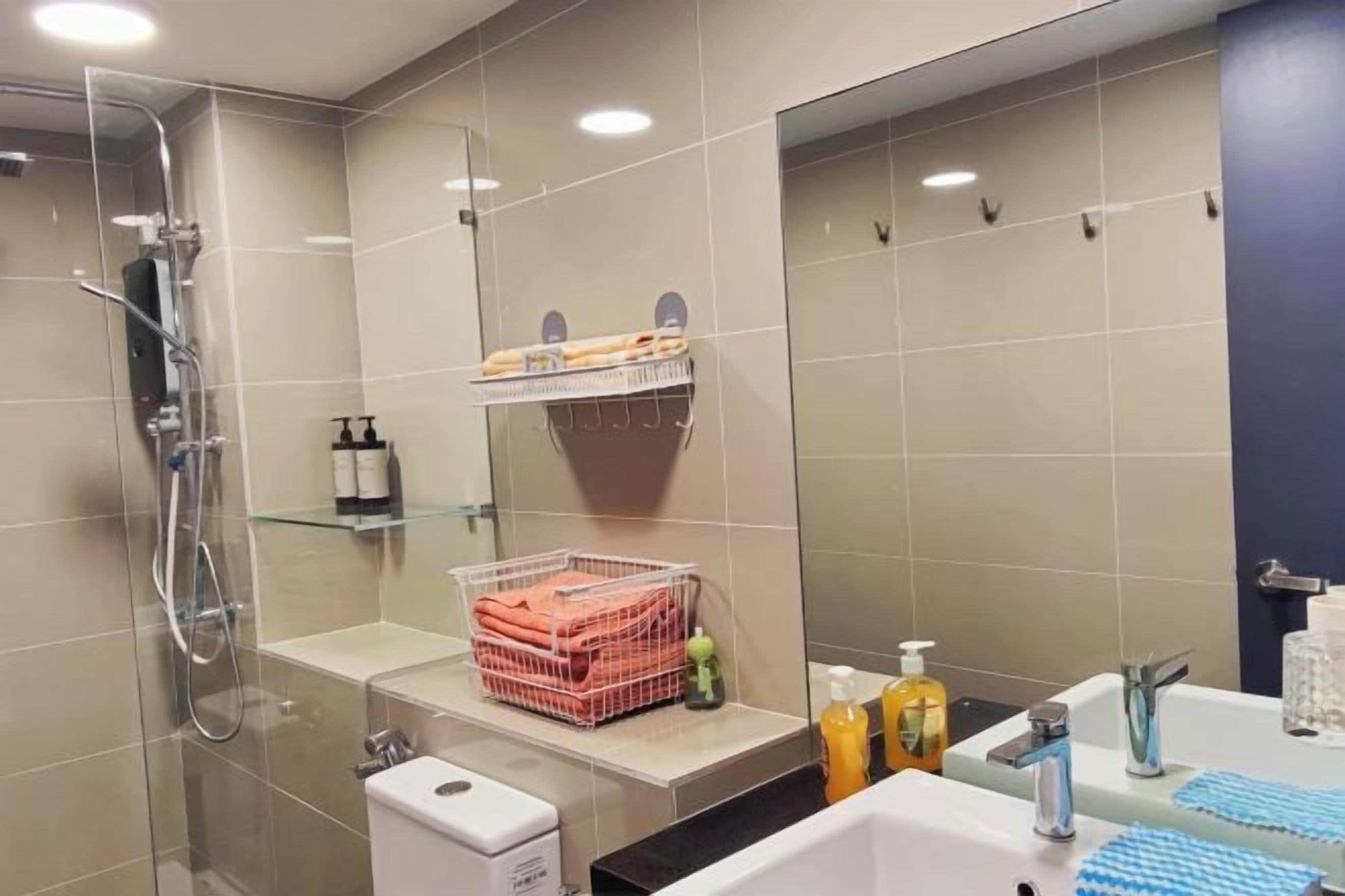 A modern bathroom with a glass shower enclosure, a sink with a mirror, and a shelf with toiletries.