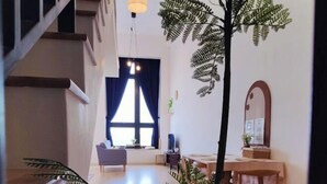 Ein modernes Interieur mit Treppe, Essbereich mit Tisch und Stühlen sowie einem großen Fenster mit Vorhängen.