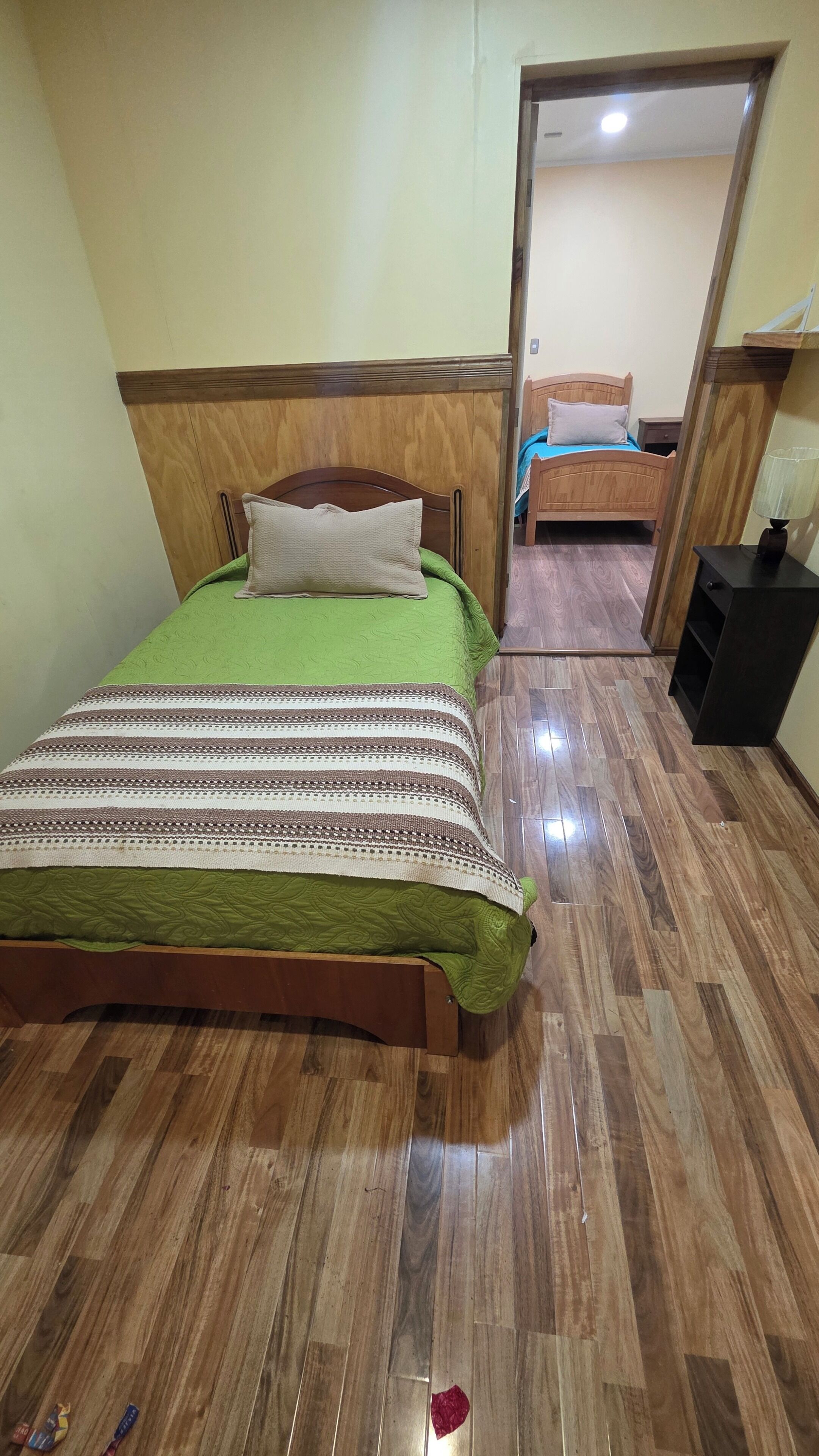 A room with a wooden bed, a wooden nightstand, and a mirror.