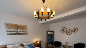 Een slaapkamer met een groot bed, houten vloeren, een kroonluchter, een schilderij en een spiegel.