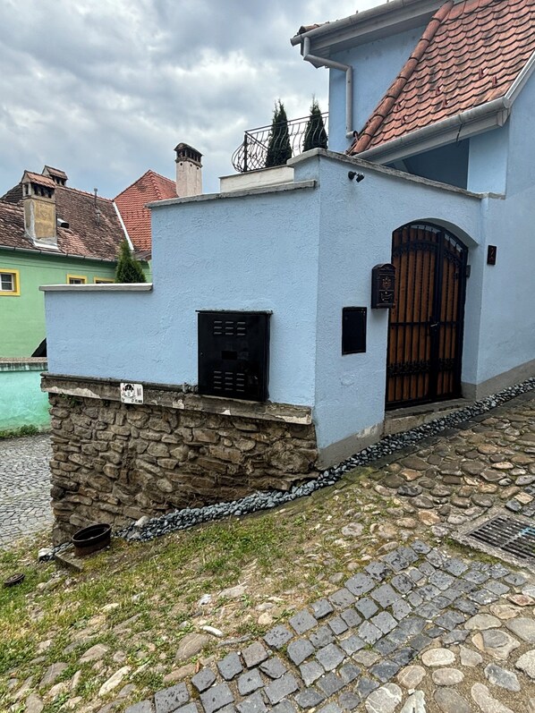 A building with a stone base and a light blue facade, featuring a black mailbox and a wooden gate. - Blue House Citadel Elite Sighisoara (Sighisoara)
