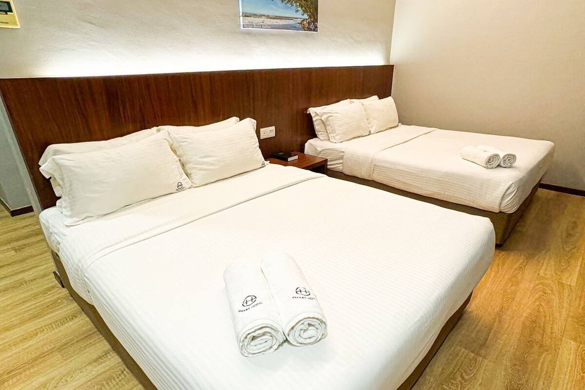 Habitación de hotel con dos camas, cada una con ropa y toallas blancas.