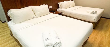 A hotel room with two beds, each with white linens and towels.