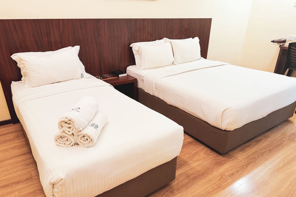 Habitación de hotel con dos camas, cabeceros de madera y suelo de madera.