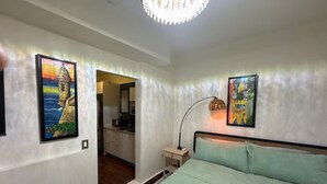 A bedroom with a bed, a nightstand, a lamp, and two paintings on the wall.