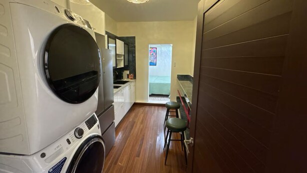 A laundry room with a washing machine, a dryer, and a small seating area with stools.