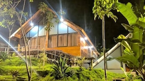 Une maison en bois avec un toit en pente, entourée d’une végétation luxuriante et d’un jardin bien éclairé.