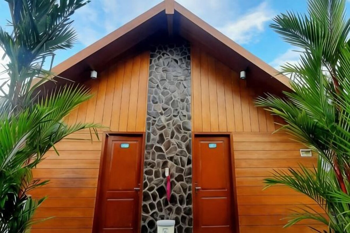 A wooden building with two doors and a stone wall.