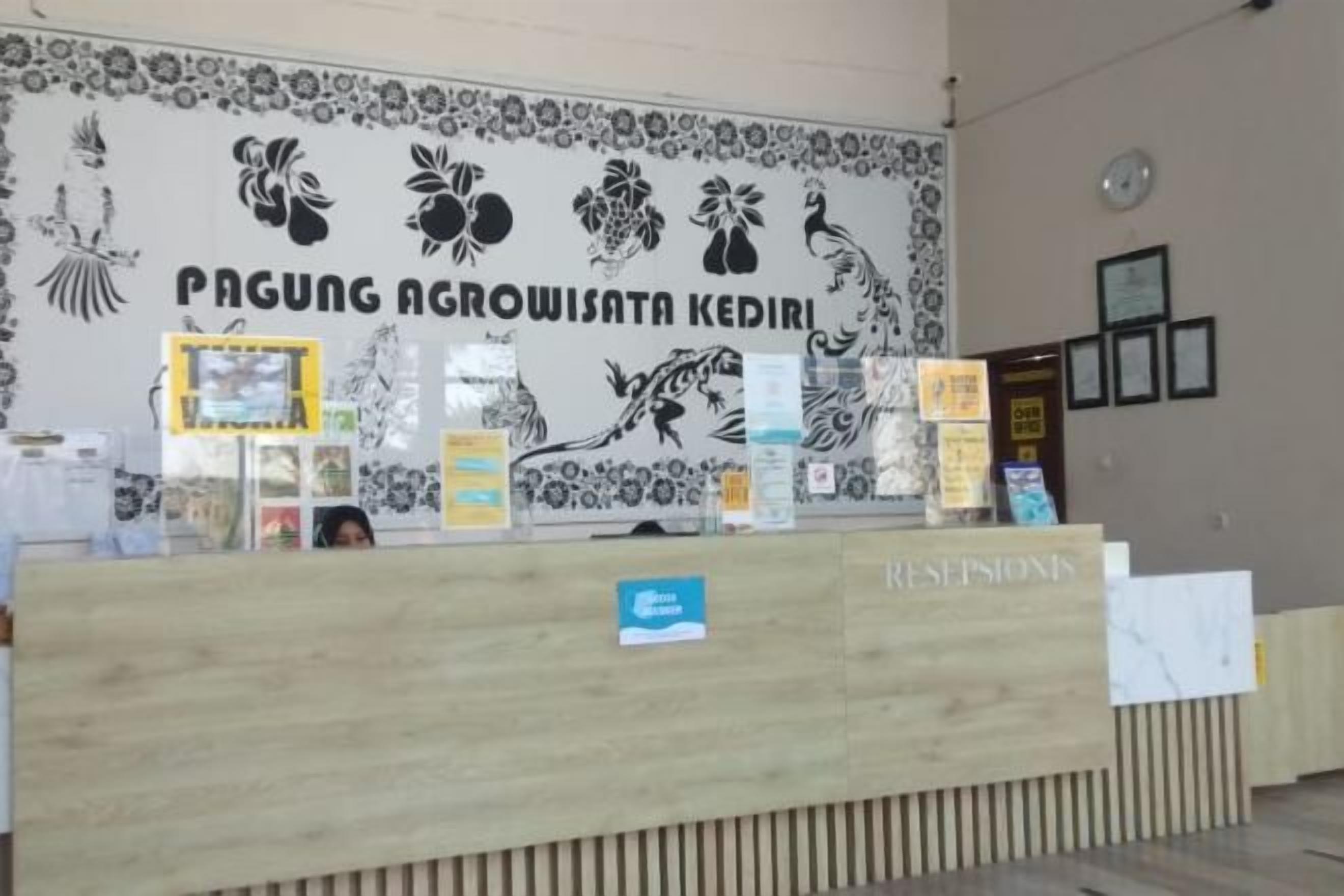 Una recepción con un mural floral y un letrero que dice 'PAGUNG AGROWISATA KEDIRI'.