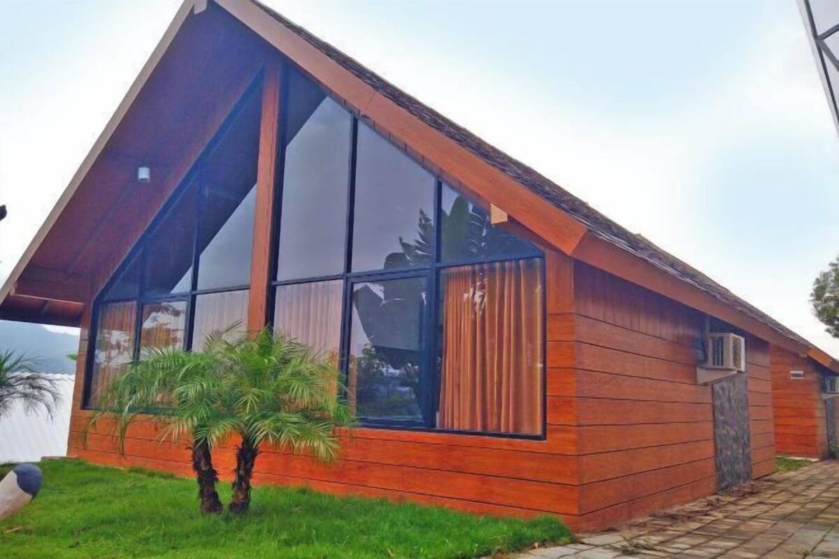 A modern building with large windows, a sloped roof, and a wooden exterior.