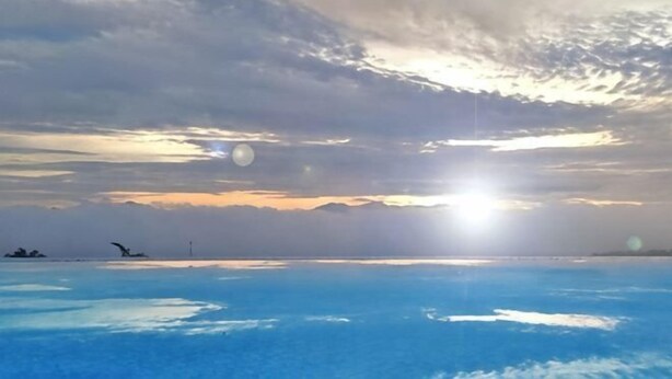 Un coucher de soleil sur une étendue d’eau, avec un ciel dégagé.