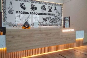 Un mostrador de recepción con un cartel que dice 'PAGUNG AGROWISATA KEDIRI' y un letrero de 'RECEPTION'.