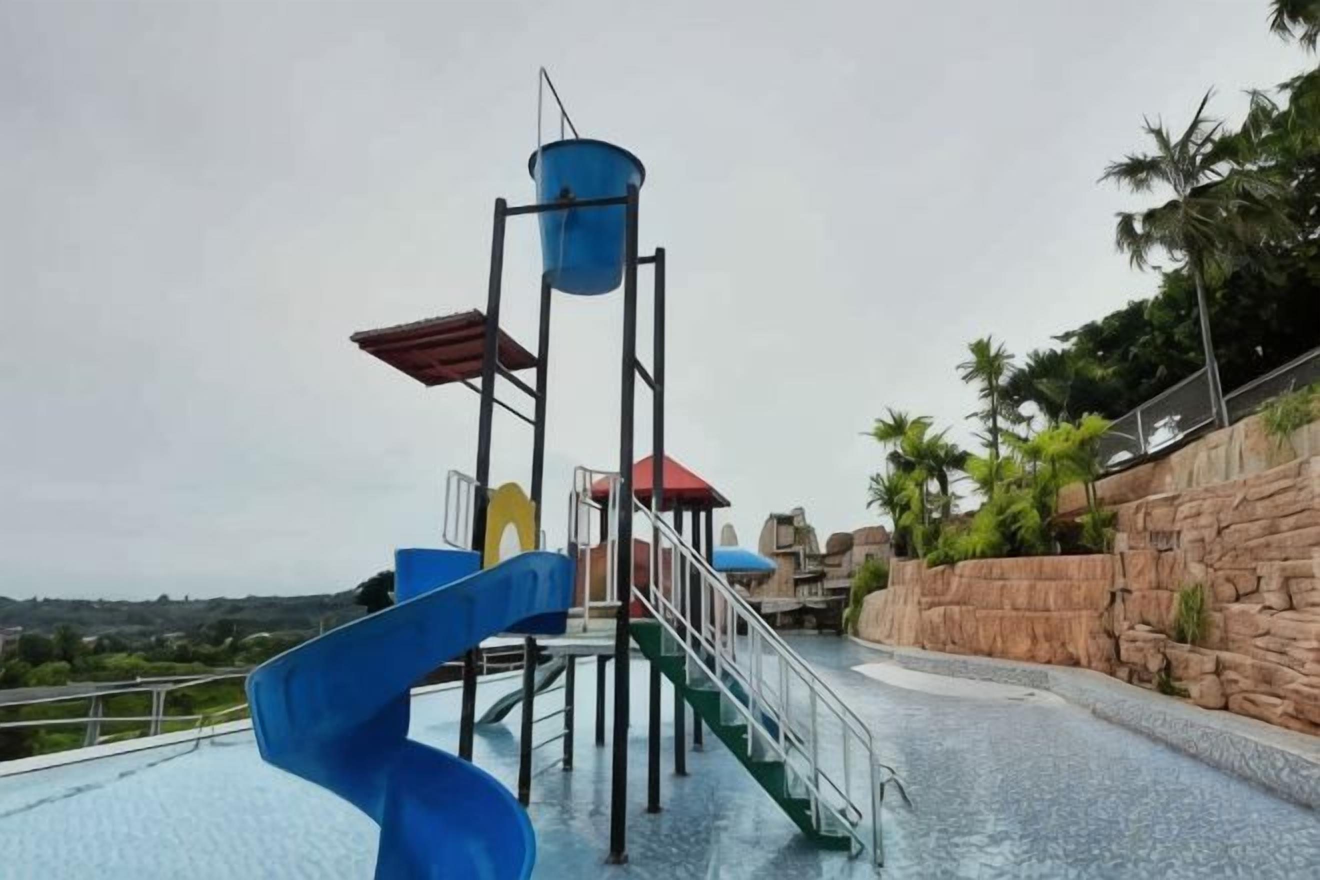 A water slide structure with a spiral design, a red roofed platform, and a blue cylindrical water tank.