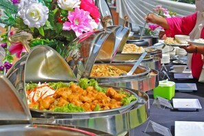 Een buffet met diverse gerechten en iemand die zich bedient.