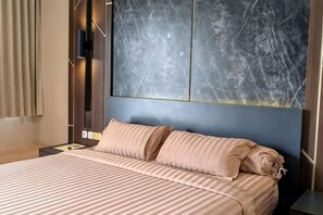 Una habitación de hotel con cama, televisor montado en la pared y un cuadro abstracto grande.