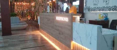 A reception area with a wooden reception desk, a marble counter, and a sign that reads 'RECEPTION'.