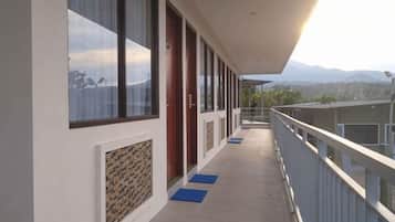 A corridor with a balcony, doors, and a view of mountains.