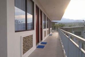 Un pasillo con balcón, puertas y vista a las montañas.