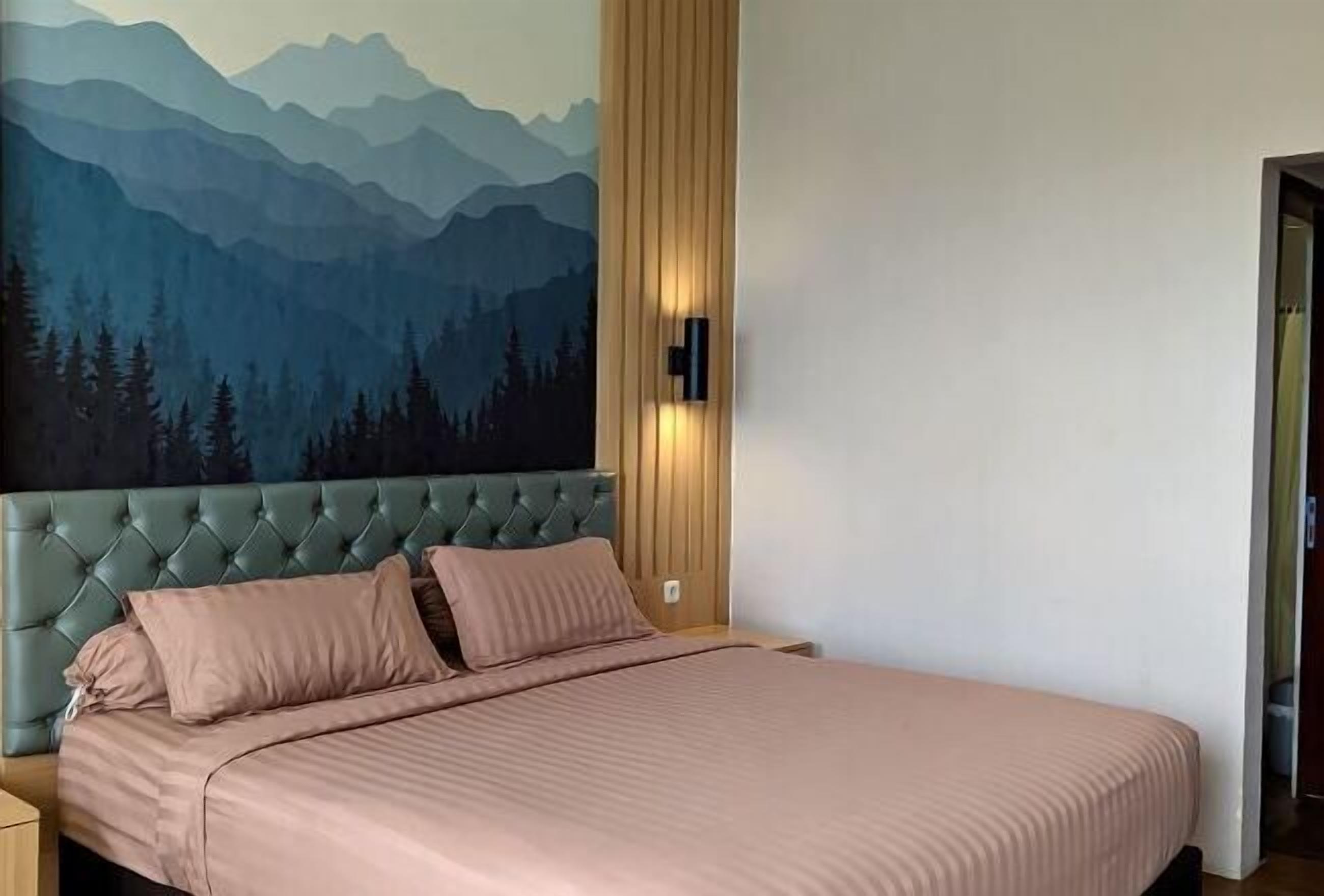 A bedroom with a mountain-themed wall mural, a tufted headboard, and a bed with pink bedding.