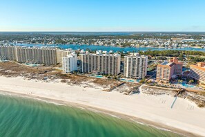 Un complejo hotelero frente al mar con varios edificios altos, una playa y un puerto deportivo.