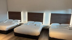 A hotel room with three beds, wooden headboards, and a light-colored floor. - Peaceful Cottage (Semporna)
