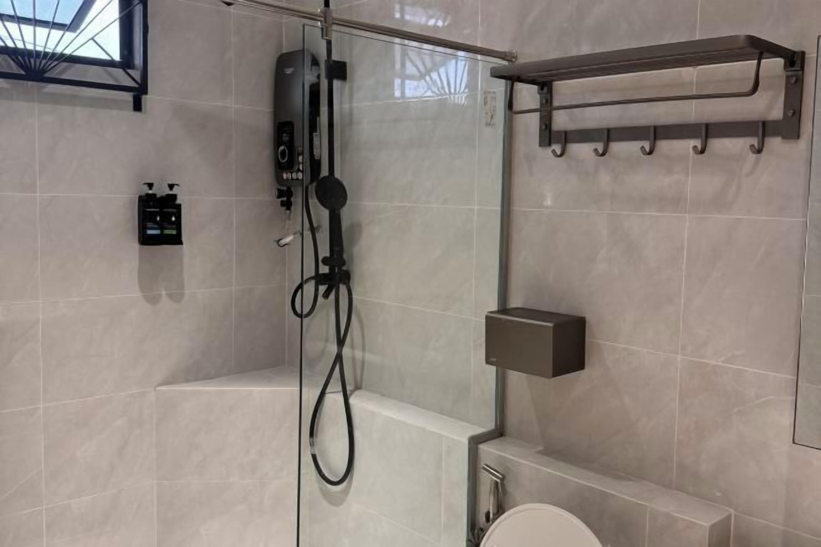 A modern bathroom with a glass shower enclosure, a toilet, a towel rack, and a soap dispenser.