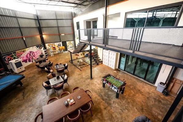 Amplio espacio interior con mesa de billar, diversas opciones de asientos y un entresuelo accesible por una escalera.
