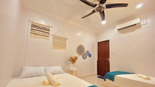 A hotel room with two beds, a ceiling fan, an air conditioning unit, and decorative wall hangings. - HeyBlueee Homestay~ 5min Jetty/Netflix/Games (Mersing)