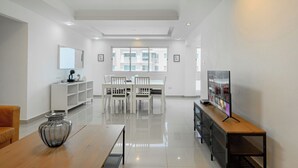 Un salon moderne comprenant un coin repas, un téléviseur et une grande fenêtre laissant entrer la lumière naturelle.