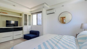 Une chambre moderne équipée d’un lit, d’une télévision, d’une armoire, d’une fenêtre et d’un appareil de climatisation.