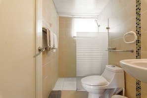 Un baño pequeño y moderno con inodoro, lavamanos y ducha.