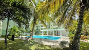 Une piscine entourée de palmiers et un bâtiment doté de nombreux balcons.