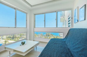 Une pièce moderne avec de grandes fenêtres, une table blanche et un canapé bleu.