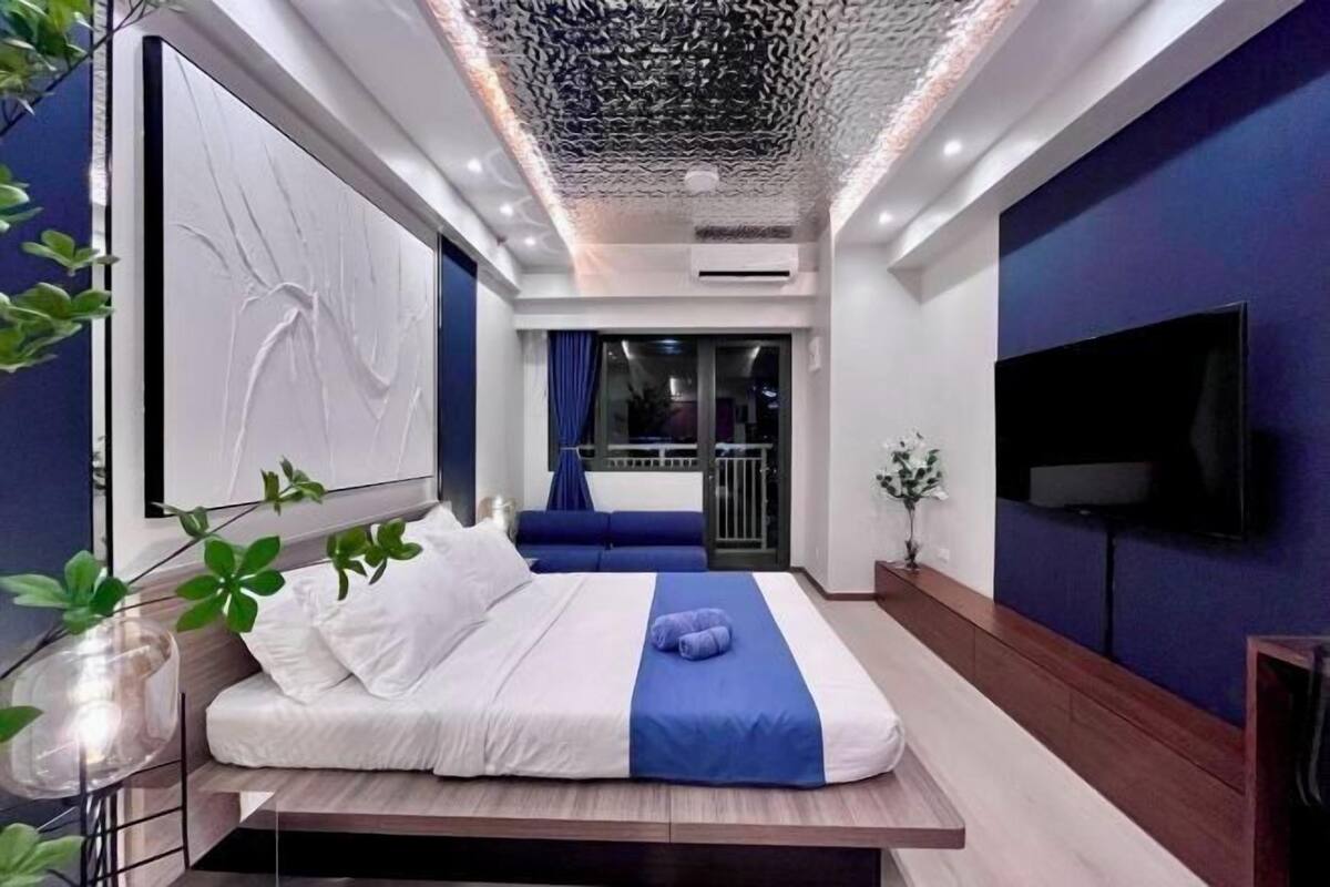 A modern bedroom with a bed, a TV, and a balcony view.