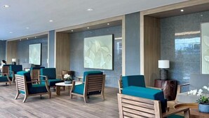 Un moderno vestíbulo de hotel con mobiliario de madera, sillones tapizados en verde y arte abstracto en la pared.