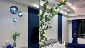 Una habitación de hotel moderna con una cama, un escritorio, un televisor y un sofá azul.