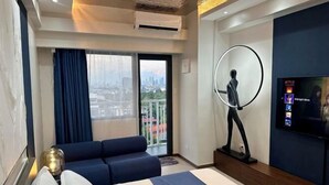 Una habitación de hotel moderna con una cama grande, un sofá, un televisor y un balcón con vistas a la ciudad.