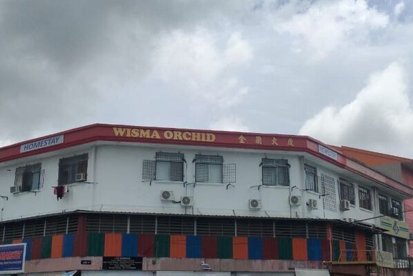 A building with a sign reading 'WISMA ORCHID' and 'HOMESTAY'.