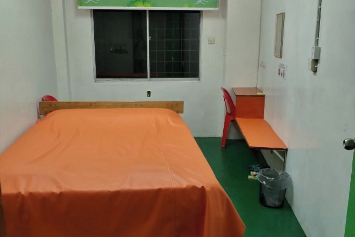 A small room with a bed, a desk, a chair, and a window.