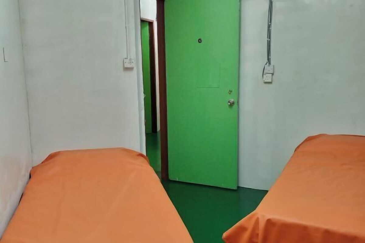 A room with two beds, a green door, and a white wall.