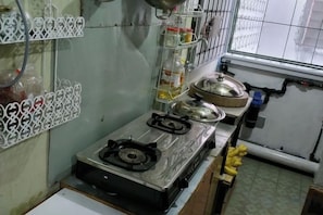 A kitchen with a gas stove, a sink, and various kitchen utensils.