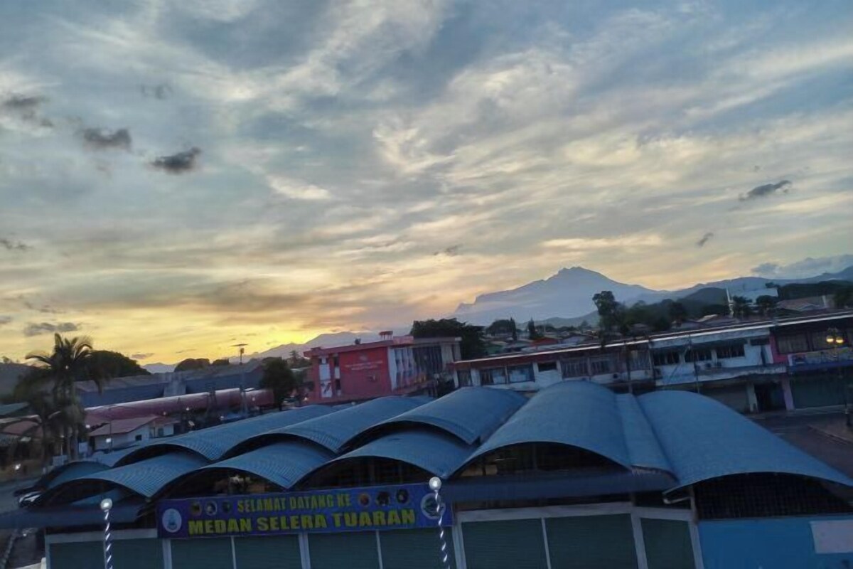 A row of buildings with curved roofs, a sign indicating a medical facility, and a mountainous backdrop.