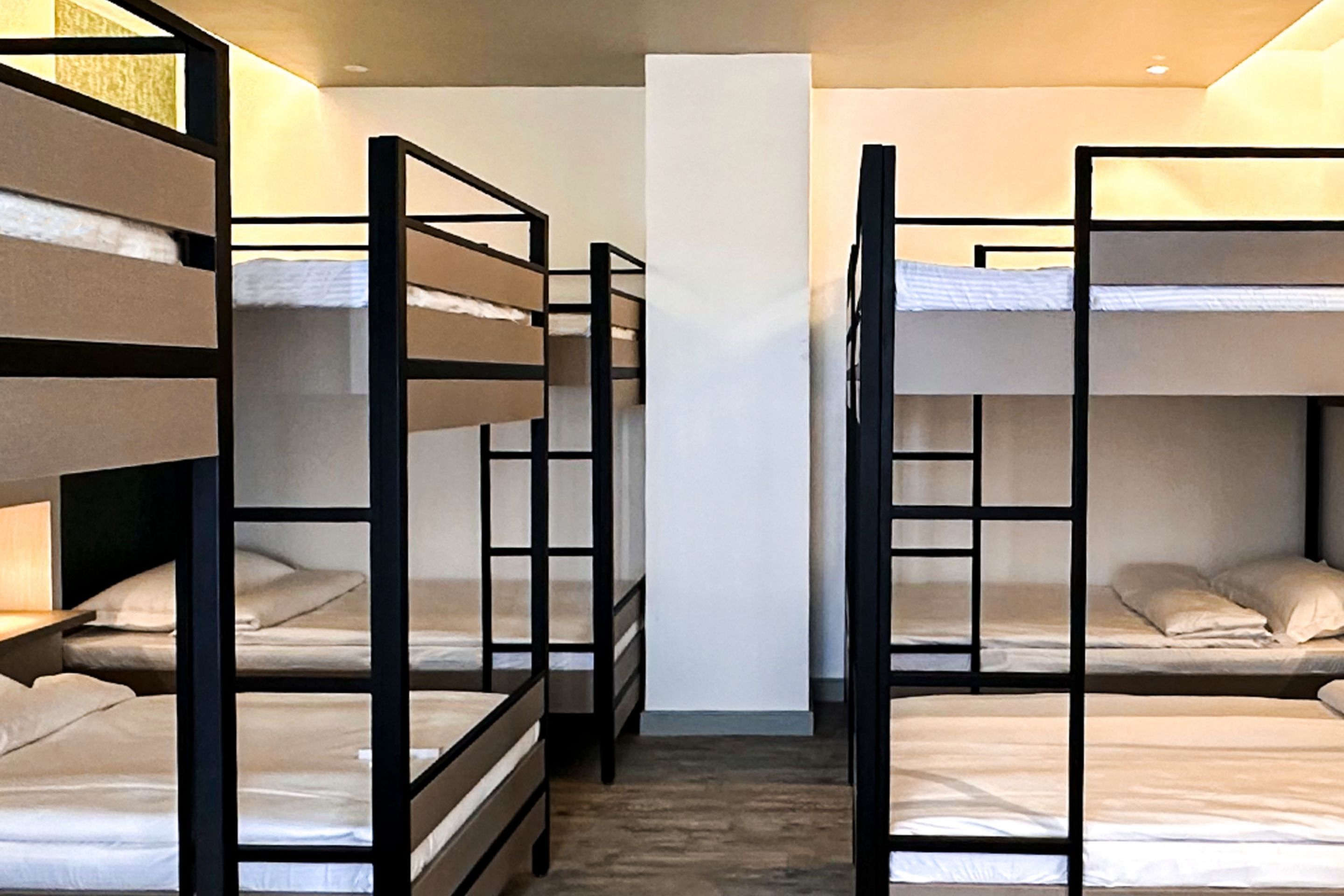 A room with bunk beds arranged in a row, a central pillar, and a wooden floor.