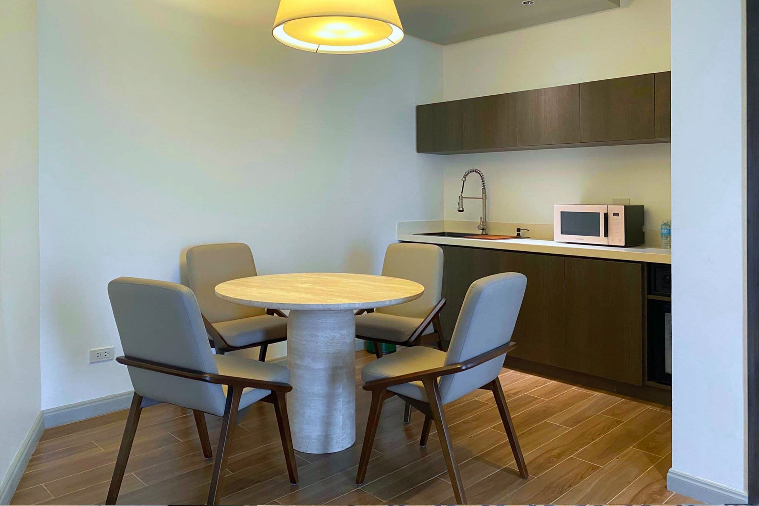 Cocina compacta con microondas, lavamanos y una mesa redonda para cuatro personas.