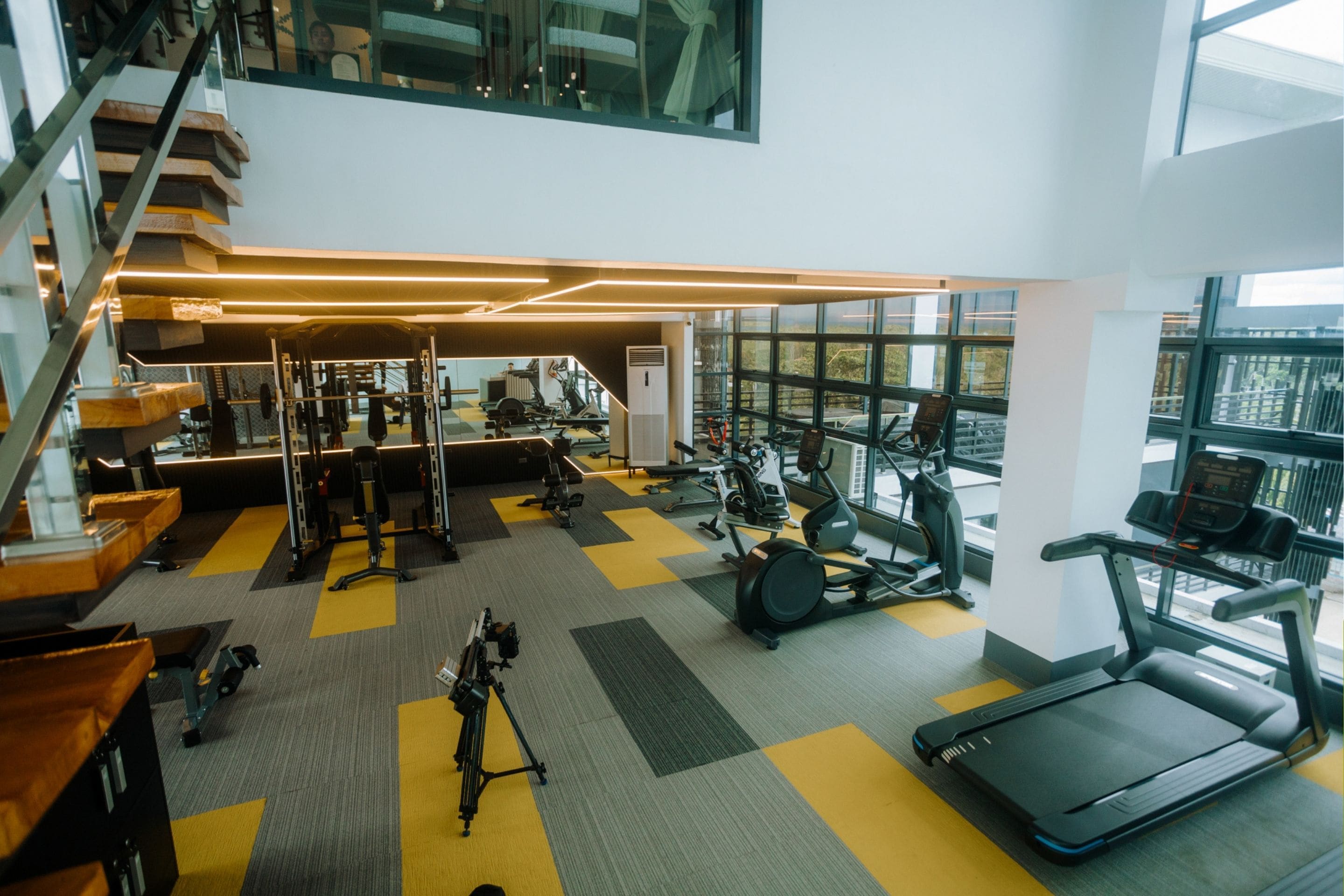 A multi-level gym with various exercise equipment, a treadmill, and a staircase.