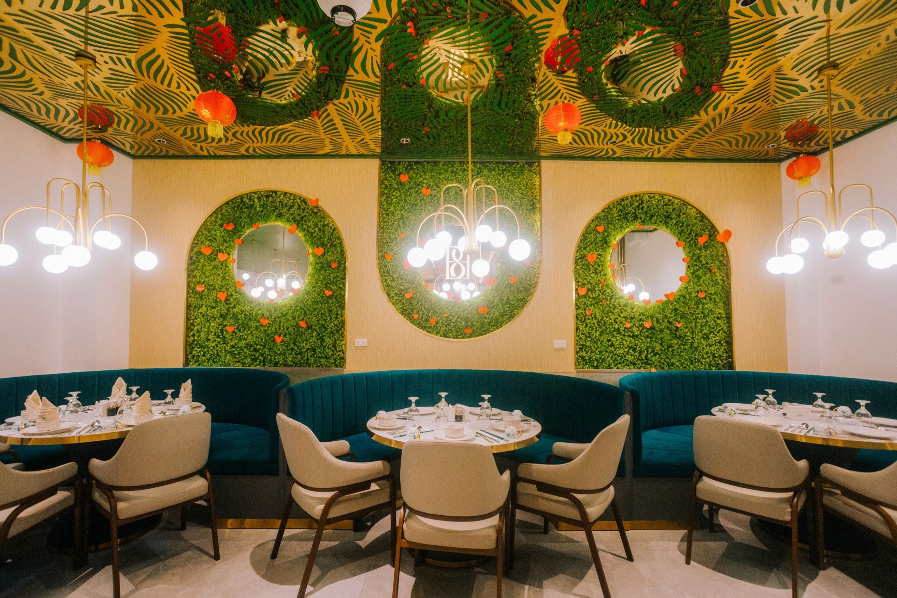 A restaurant interior with round tables, teal booths, and decorative wall mirrors.