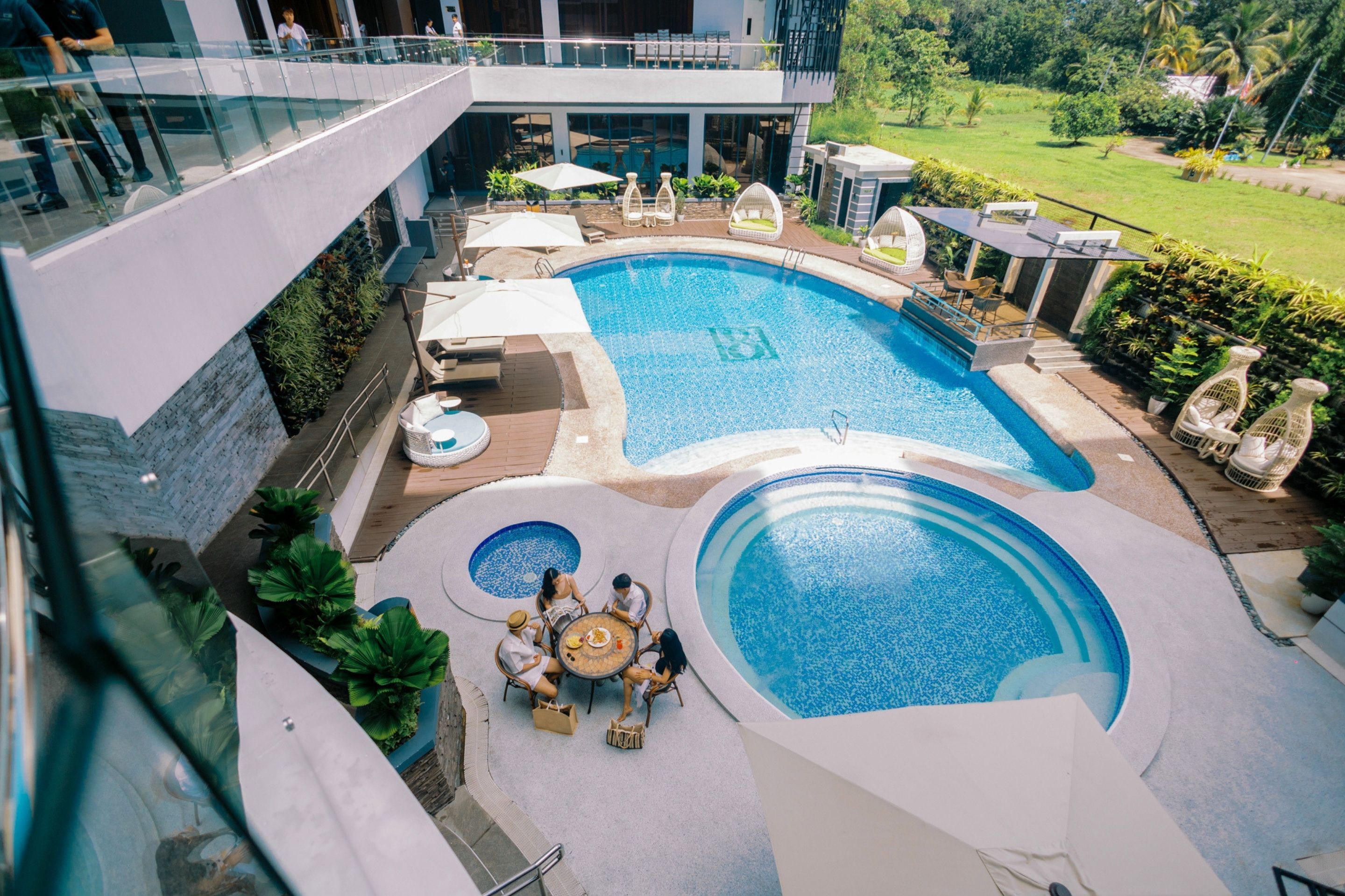 A rooftop pool area with multiple swimming pools, lounge chairs, and a dining table.